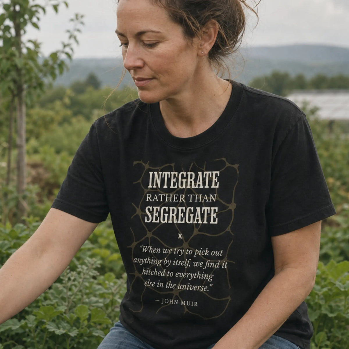 Don't Segregate organic cotton t-shirt worn by woman among polyculture companion plantings on a regenerative farm